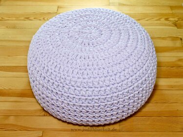 Rundes pastell-lila gehäkeltes Bodenkissen auf Holzfußboden