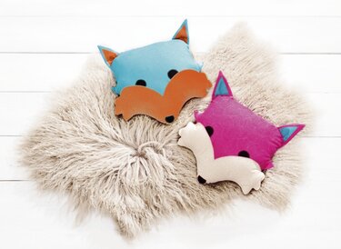 Fuchskissen in Blau-Orange und Pink-Creme auf flauschigem Untergrund