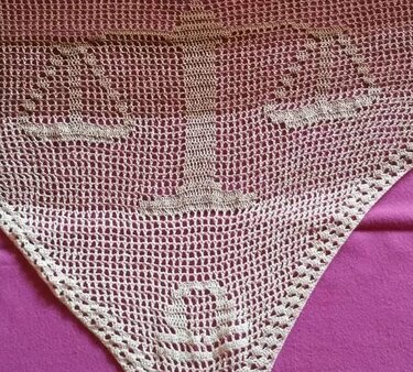 Dreieckiges beigefarbenes Häkeltuch mit Anker-Motiv auf violettem Untergrund.