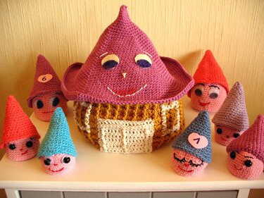 Mehrere gehäkelte Wichtelfiguren mit spitzen Hüten und ein größeres Wichtelhaus mit Gesicht