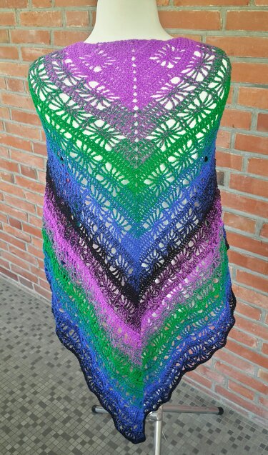 Gehäkeltes Dreieckstuch in Farbverlauf (violett, grün, blau, schwarz) mit Lochmuster auf Schneiderpuppe vor Ziegelwand