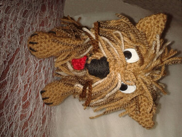 Gehäkelter brauner Amigurumi-Hund mit fransigem Garnfell, schwarzer Nase und roter Zunge
