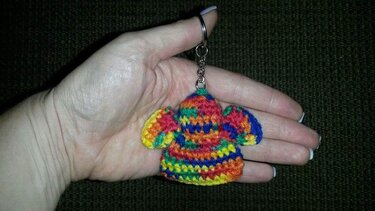 Hand hält gehäkelten bunten Regenbogen-Schlüsselanhänger mit Metallring