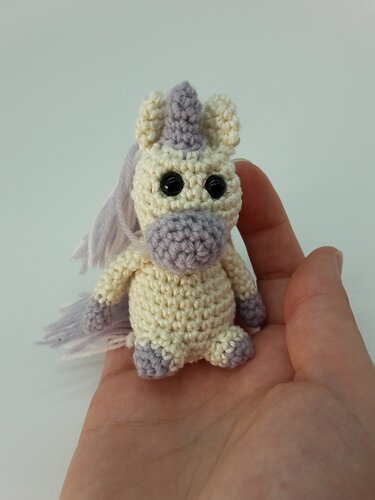 Kleines, schnell gehäkeltes Einhorn-Amigurumi in einer Hand gehalten