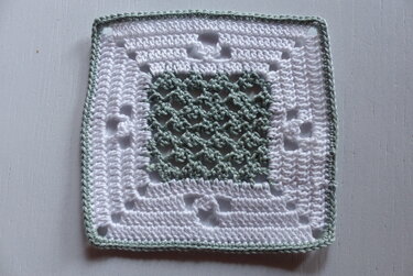 Gehäkeltes Granny Square in Weiß mit pastellgrünem Netzzentrum und schmaler Borte