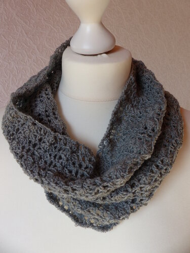 Grau gehäkelter Loop-Schal mit offenem Muster auf weißer Schaufensterpuppe