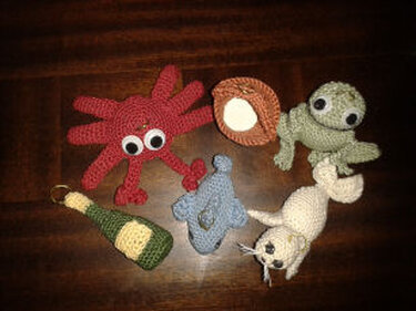 Handgehäkelte Amigurumi-Figuren: Oktopus, Robbe, Delfin, Muschel und Flasche.