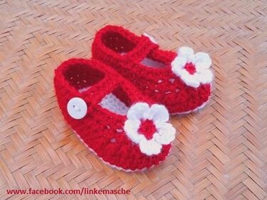 Rote gehäkelte Babys-Ballerinas mit weißer Blüte und Knopf am Riemen