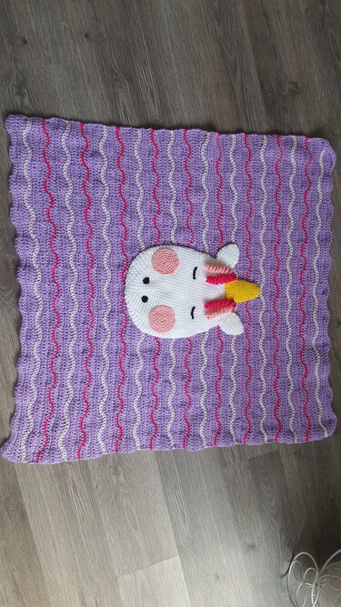 Lila gehäkelte Babydecke mit Wellenmuster und weißer Einhorn-Applikation mit gelbem Horn