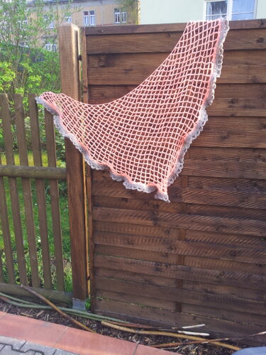 Rosa gehäkeltes Dreieckstuch mit grauer Wellenborte, an einem Holzzaun hängend