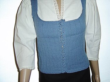 Hellblaues gestricktes Mieder mit quadratischem Ausschnitt und Zierschnürung vorne auf einer Schaufensterpuppe über einer weißen Spitzenbluse.