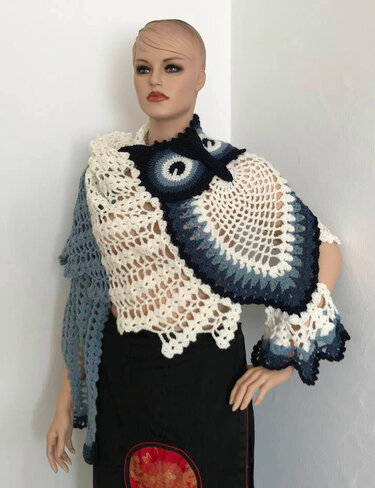 Mannequin wearing cream triangle crochet shawl with navy-to-light-blue ombre owl motif corner and scalloped edges