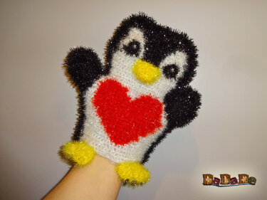 Hand in gehäkeltem Pinguin-Handschuh mit rotem Herz, gelbem Schnabel und gelben Füßchen