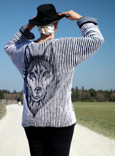 Rückenansicht einer schwarz-weiß gestreiften Strickjacke mit Blumenmotiv