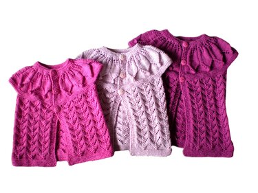 Drei gestrickte Babyjäckchen in Rosa, Lavendel und Magenta mit Lochmuster und passenden Knöpfen.