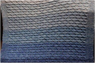 Nahaufnahme einer gestrickten Babydecke mit Wabenmuster, kraus-rechtem Rand und Farbverlauf von Hellgrau zu Dunkelblau