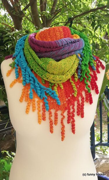 Mannequin wearing a rainbow gradient crochet triangle shawl with curly spiral fringe