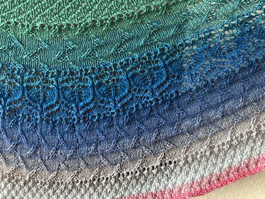 Halbrundförmiges gestricktes Tuch in Grün-, Blau- und Rosatönen mit Ajour- und Strukturmustern