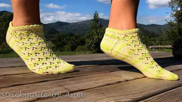 Gestrickte neongelbe Knöchelsocken mit Lochmuster auf Holzplanken