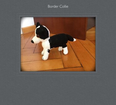 Gehäkeltes Border-Collie-Amigurumi in Schwarz-Weiß auf Holzboden