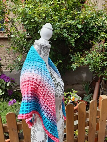 Schaufensterpuppe mit gehäkeltem Dreieckstuch in Blau-Rosa vor Gartenzaun