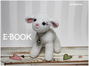 Vollansicht eines weißen gehäkelten Lämmchens mit kleiner Glocke um den Hals, auf einer Holzoberfläche; im linken Bereich des Bildes steht 'E-BOOK'.