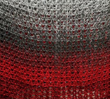 Nahaufnahme eines gehäkelten Netzstichs mit Farbverlauf von Grau zu Rot