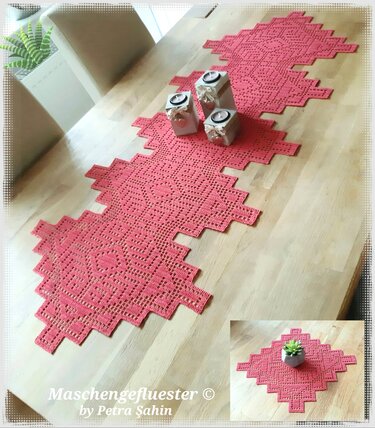 Gehäkelter korallenfarbener Tischläufer und ein passendes Deckchen mit geometrischem Rautenmuster und gezackten Kanten auf hellem Holztisch, dekoriert mit Kerzenhaltern.