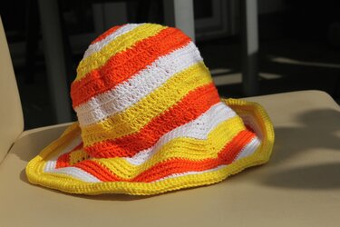 Gehäkelte Kinder-Sonnenmütze mit gelben, orangen und weißen Streifen und breiter Krempe