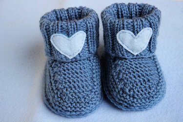 Pair of blue-gray knitted baby booties with white heart appliqués