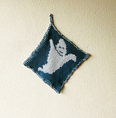 Quadratischer gestrickter Topflappen in dunklem Blau mit weißem Geist‑Motiv und Aufhängeschlaufe.