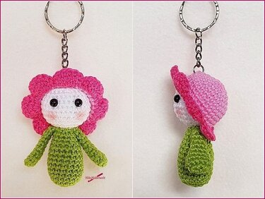Gehäkelter Blumen-Amigurumi Schlüsselanhänger mit rosa Blüten, weißem Gesicht, schwarzen Augen und grünem Körper, am Metallring