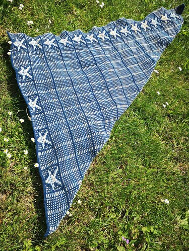 Nahaufnahme eines gestrickten Dreieckstuchs mit Karomuster und weißen Sternen