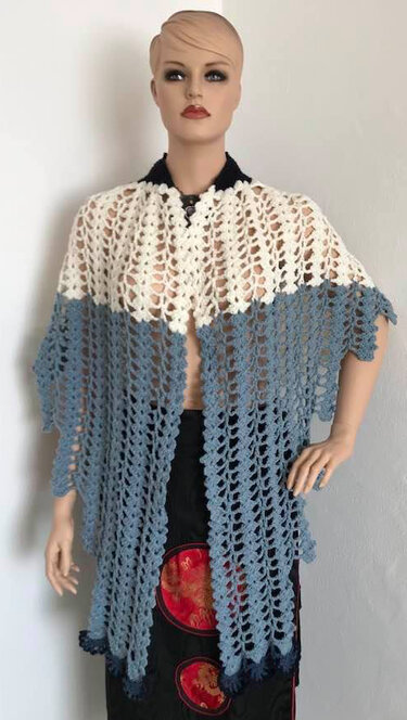 Mannequin wearing a two-tone crochet triangle shawl in cream and blue with a scalloped edge