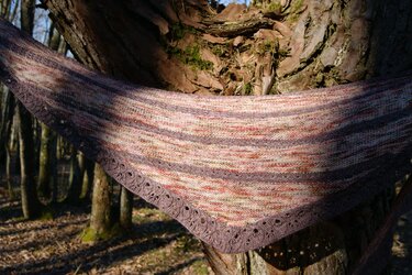 Gestricktes Dreieckstuch in Beige, Rosa und Violett mit Lochmuster-Borte über Baumstamm drapiert