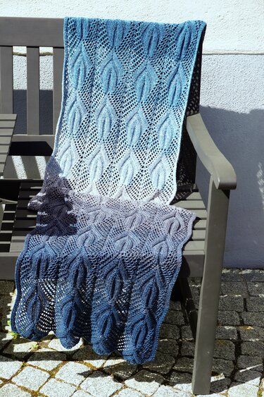 Knitted lace shawl with leaf pattern, openwork, and scalloped edge in blue gradient