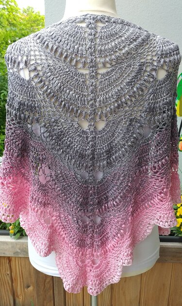 Back view of a grey-to-pink ombre crocheted triangle shawl on a mannequin, showing openwork lace stitches and scalloped edge.