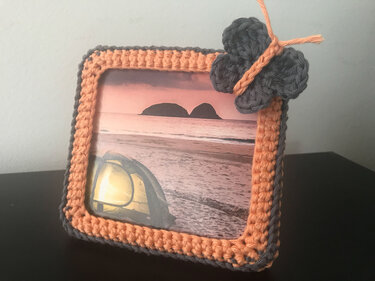 Rechteckiger gehäkelter Bilderrahmen in Pfirsich und Grau mit Schmetterling oben rechts