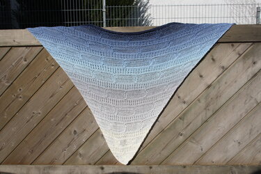 Gehäkeltes Dreieckstuch in Blau-Weiß an Holzzaun