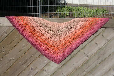 Gehäkeltes Dreieckstuch mit Farbverlauf von Beige über Orange bis Rosa, auf Holzlatte gespannt