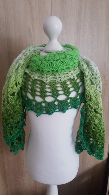 Halbrundes gehäkeltes Schultertuch in Grüntönen auf einer weißen Schaufensterpuppe mit Ajour- und Blattmuster