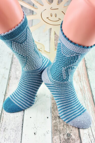 Paar gestrickter türkis‑grauer Damensocken mit Wabenstruktur am Schaft und gestreiftem Fuß auf Strumpfpuppen