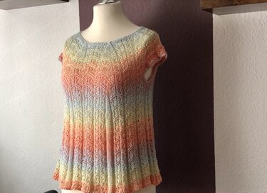 Gestricktes Damen-Kurzarmshirt auf Schneiderpuppe mit pastellfarbenem Farbverlauf und filigranem Lochmuster