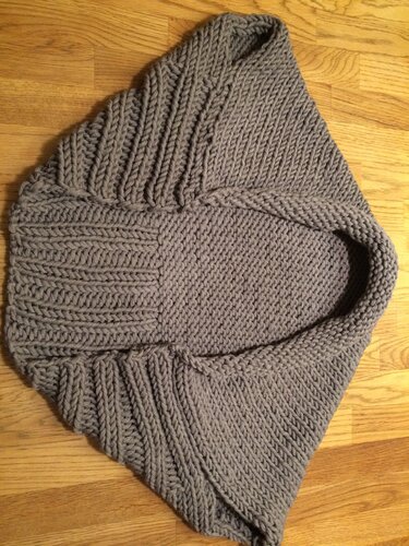 Grau gestrickter Kapuzenponcho für Kinder liegend auf Holzfußboden