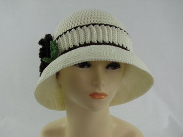 Cremefarbener gehäkelter Damen-Sonnenhut mit braunen Streifen und grüner Blüte auf Schaufensterkopf
