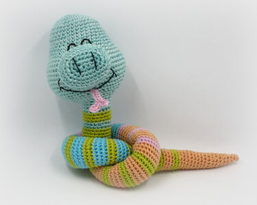 Gehäkelte Amigurumi‑Schlange, hellblauer Kopf, pastellgestreifter Körper, rosa Zunge