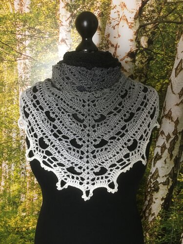 Gray to white ombre crocheted triangle shawl with lace openwork and scalloped edge on a black mannequin