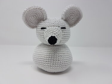 Hellgraue gehäkelte Amigurumi‑Maus mit großen Ohren, geschlossenen Augen und schwarzer Nase auf weißem Hintergrund.