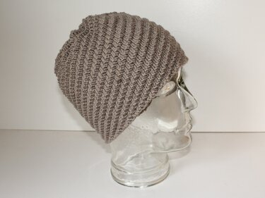 Gestrickte Slouch‑Mütze in Taupe mit schrägem Rippenmuster auf Glaskopf