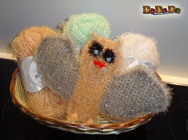 Kuschelige gehäkelte Eule mit großen, dunklen Augen und oranger Schnabelimitierung im Korb